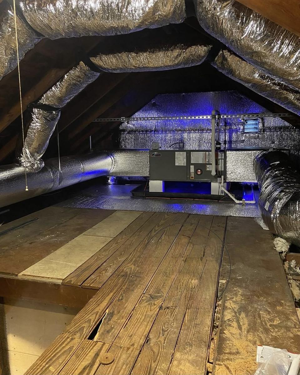 Attic HVAC installation with ultraviolet air treatment lighting and insulated ductwork.