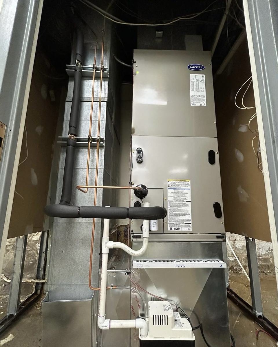 New Carrier air handler installed in a closet with refrigerant lines and condensate pump by Jordan Heating and Air Conditioning.